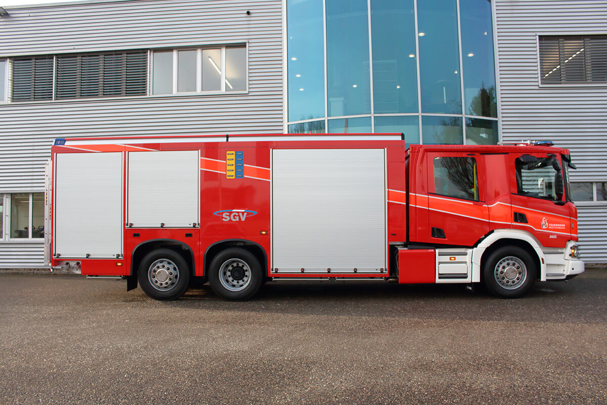 Seitenansicht eines Löschfahrzeugs vor einer Feuerwache.